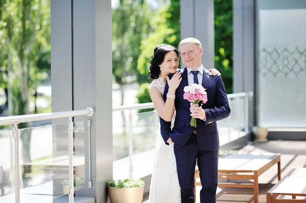 Bride embraces the groom's shoulder. The bride with a wedding bo