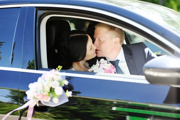 Bride and groom kissing in wedding car