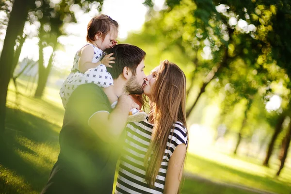 Young family on the walk. Little daughter sits on the shoulders