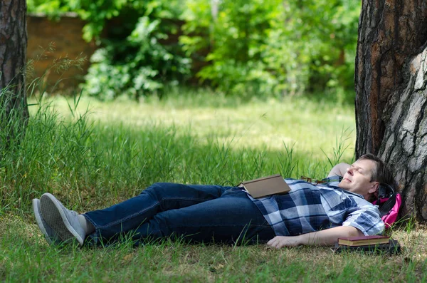 Man sleeps with open book on lawn at old pine