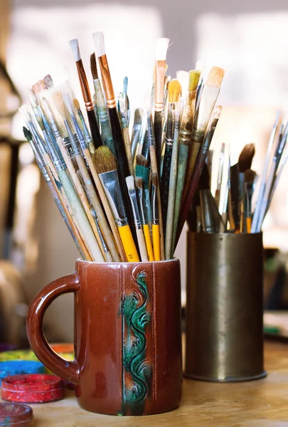 Paint brushes in jar standing on table in workshop