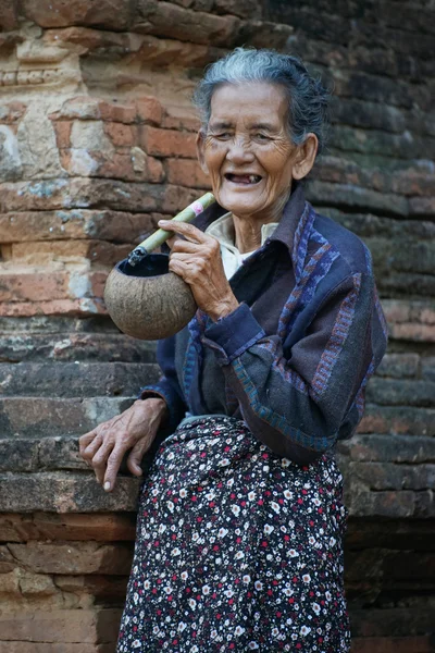 Unidentified local old wrinkled woman smoking traditional tobacco