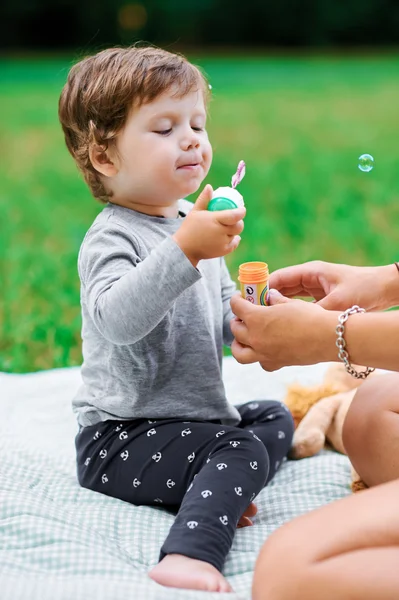 Little boy make a soap bubbles in park in summer