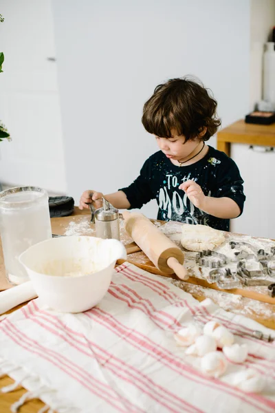 Little boy in the kitchen helping to cook the dough for baking