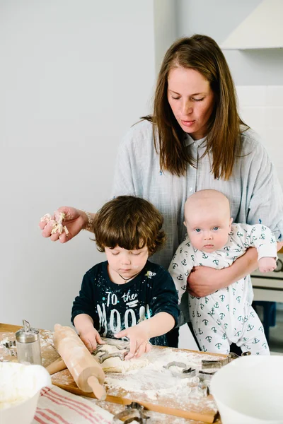 Young and happy mom with her children in the kitchen cook cookie