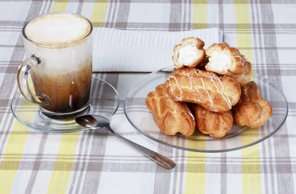 Cappuccino with eclairs, tablecloth, cup