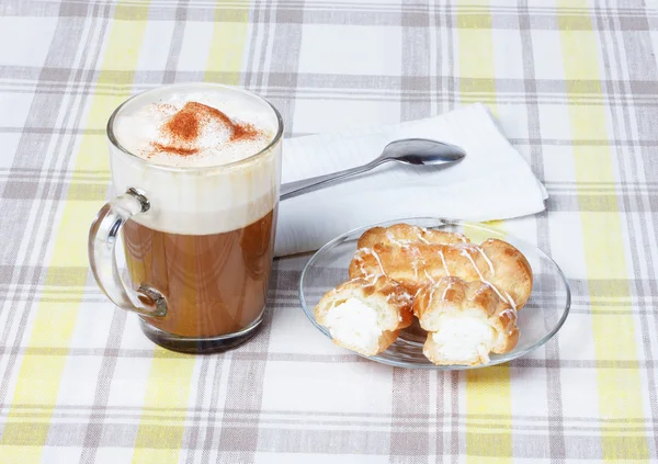 Cappuccino with eclairs, tablecloth, cup