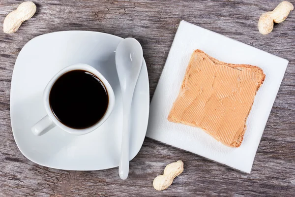 Sandwich with peanut butter on a paper napkin, cup of coffee, pe