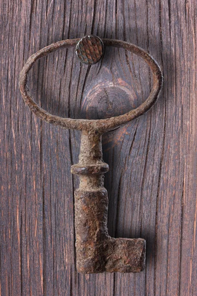 Old rusty key hanging on the wall, metal, rust, nail.