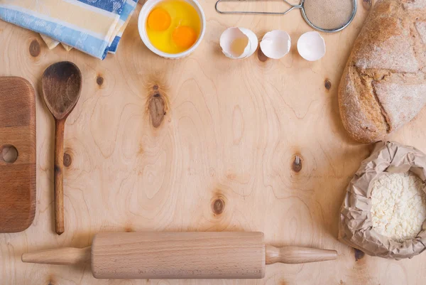 Baking background with cutting board, eggshell, flour, rolling p