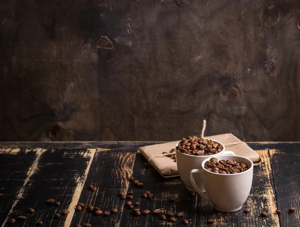 Cup with coffee beans at dark wooden background