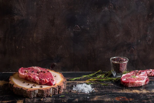 Raw juicy meat steak on dark wooden background ready to roasting