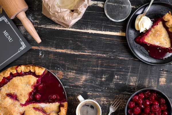 Cherry pie, cup of coffee on dark rustic background