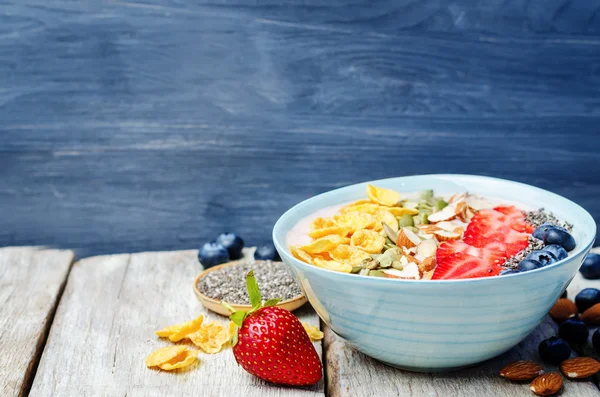 Healthy strawberry smoothie bowl with fruits, cereals, seeds and