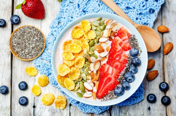 Healthy strawberry smoothie bowl with fruits, cereals, seeds and