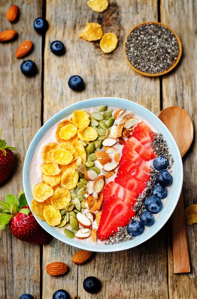 Healthy strawberry smoothie bowl with fruits, cereals, seeds and