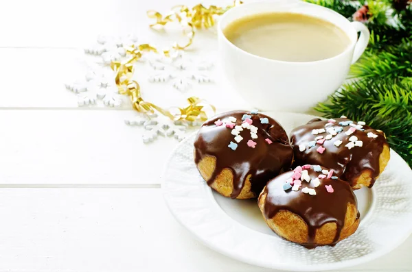 Profiteroles with chocolate icing and colored powder and coffee