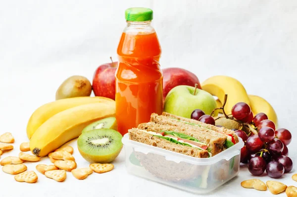 School lunch with a sandwich, fresh fruits, crackers and juice