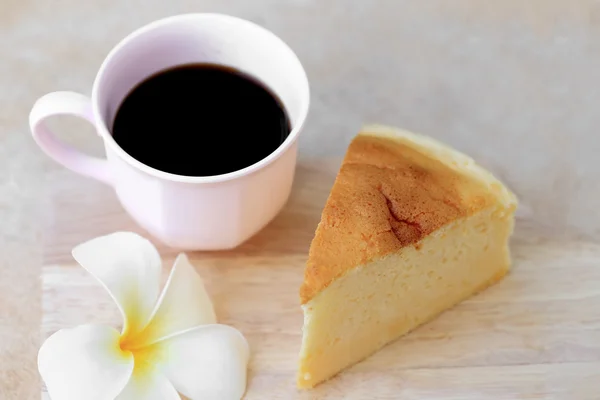 Pieces of Japanese style Cheesecake and cup of black coffee on wooden plate.
