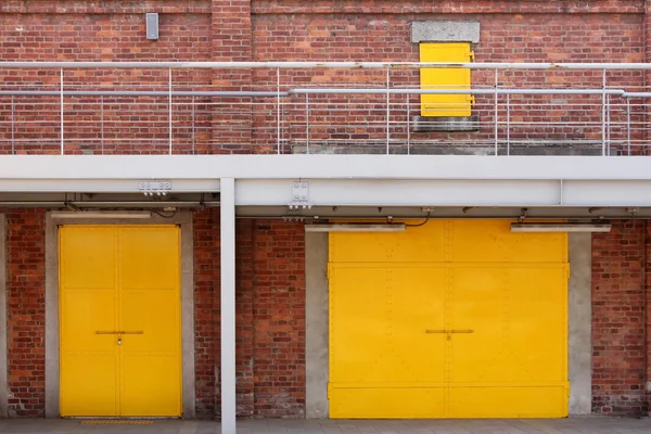 Metal yellow factory door on brick wall