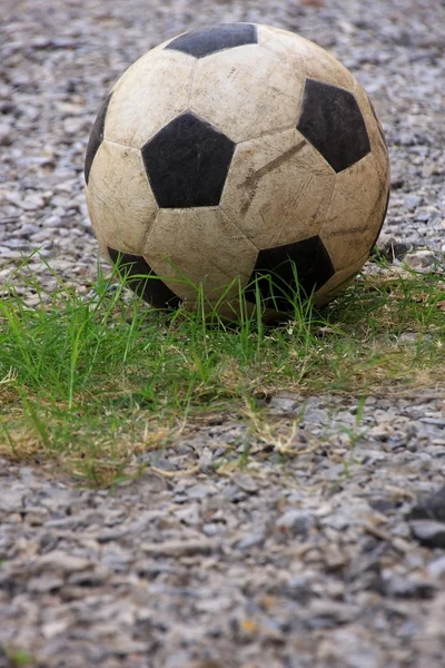 An old football or soccer ball on crushed gravel yard.