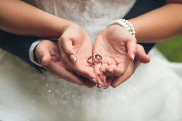 Wedding rings in hands of groom and bride