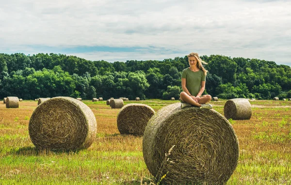 Young blond girl sitting on haystack
