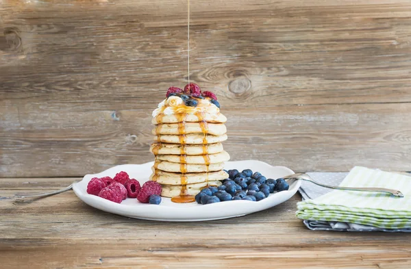 Pancakes with creamy cheese topping, garden berries and maple sy