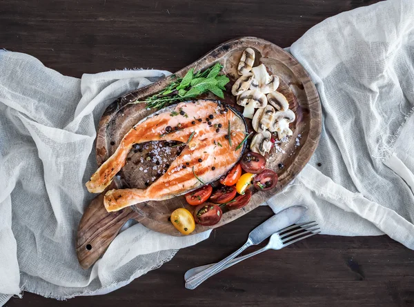 Grilled salmon steak with fresh herbs, roasted mushrooms, cherry