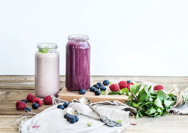 Fresh healthy smoothie with blueberries, raspberries in glass jars and mint
