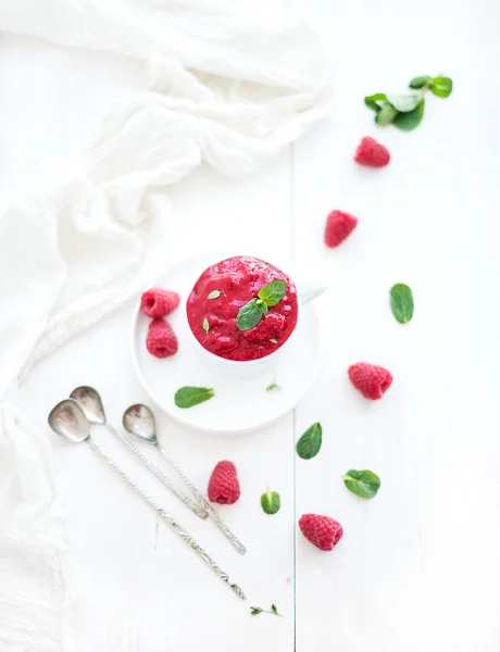 Raspberry sorbet ice-cream with mint leaves  and spoons on white background