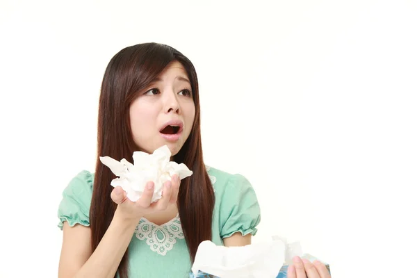 Young woman with an allergy sneezing into tissue