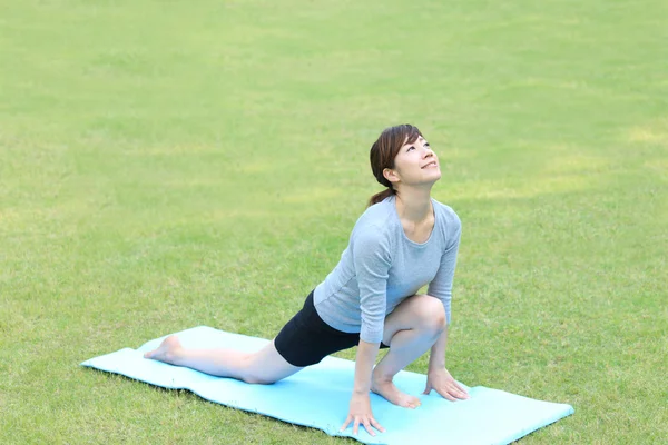 Japanese woman outside doing yoga High Lunge