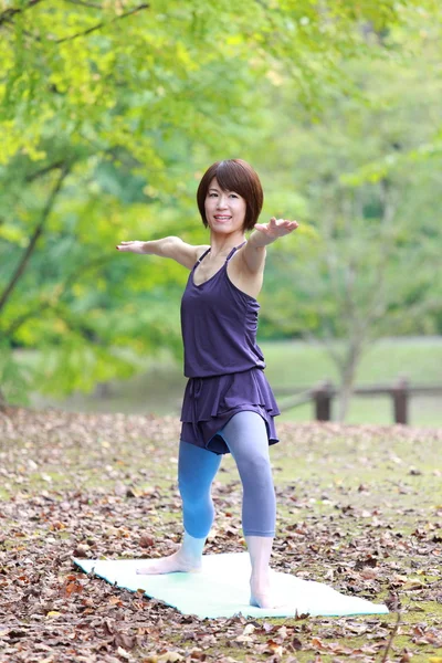 Japanese woman outside doing yoga warrior II pose