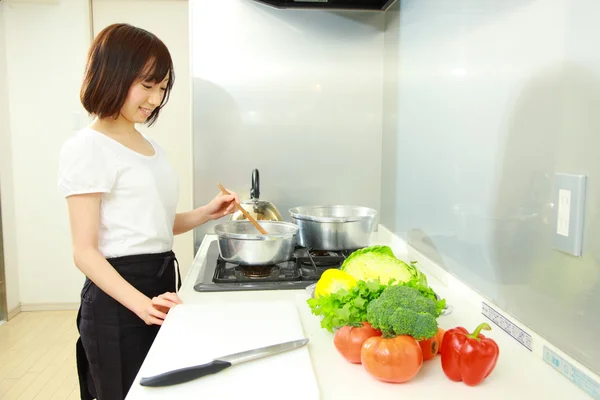 Young Japanese woman cooks in kitchen