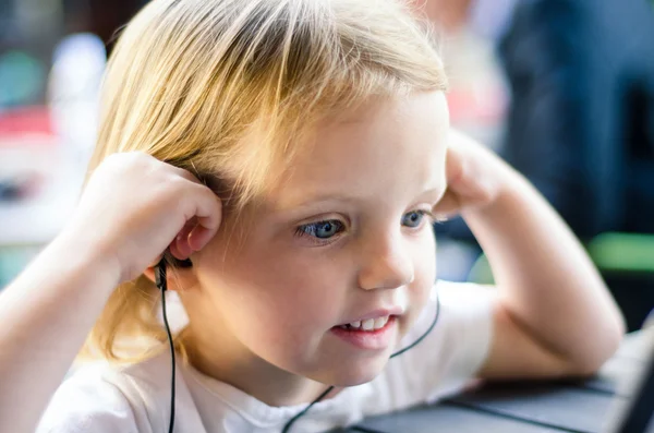 Little girl watching tablet or pc with earphones. Little girl en