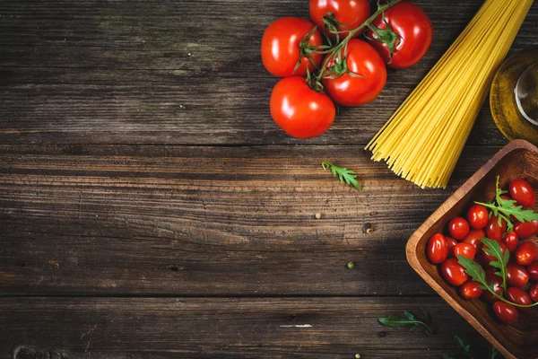 Food background with tomatoes, dry pasta, olive oil