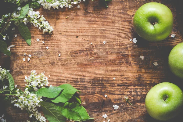 Spring / summer background with flowers and green apples on wooden backdrop.