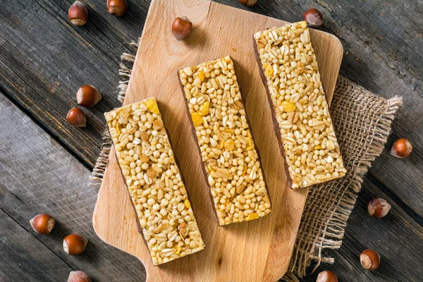 Granola bars with grains, nuts and dried fruit on wooden cutting board