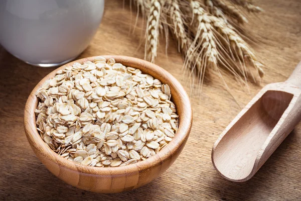 Oats, rolled oats or oat flakes in wooden bowl