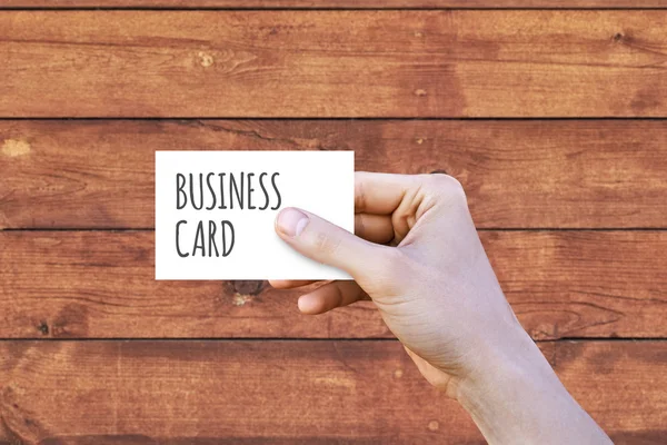 Hand holding business card on wood background
