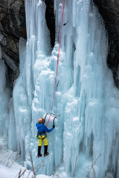 Brave ice climber climbing a iced waterfall in italian alps