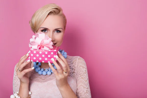 Happy birthday. Sweet blonde woman holding small gift box with ribbon. Soft colors