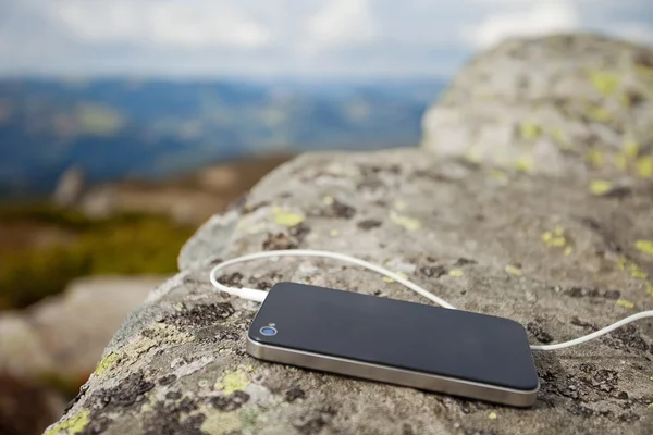 White earphones with smartphone on moss-covered stone