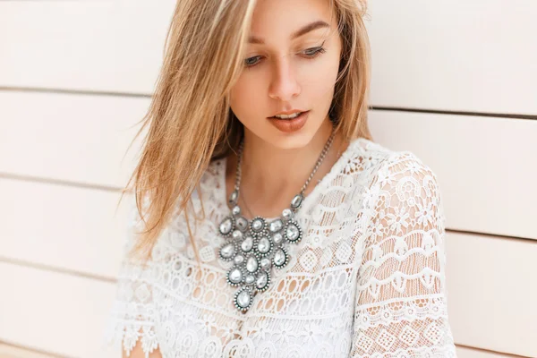 Pretty modest woman in vintage lace blouse standing near a white wooden wall