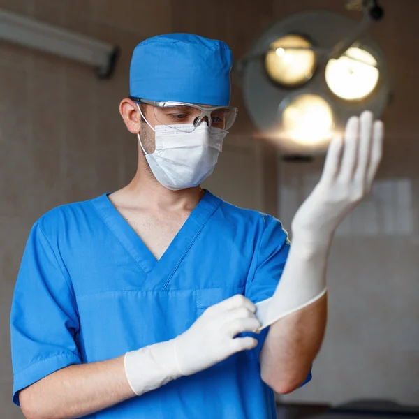 Doctor puts a glove on his hand. Surgeon preparing for surgery.