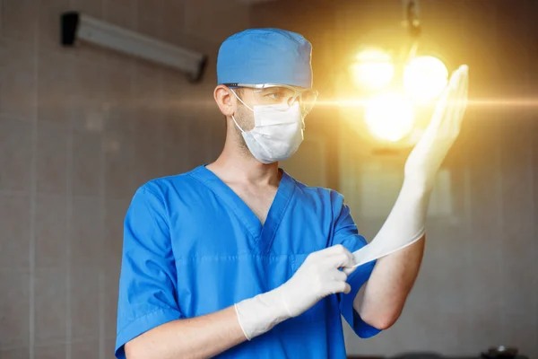 Professional Doctor to prepare for surgery. The surgeon corrects a rubber glove on a background of operating with bright light