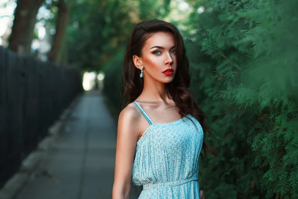 Beautiful fashion woman walking in the park in a turquoise dress