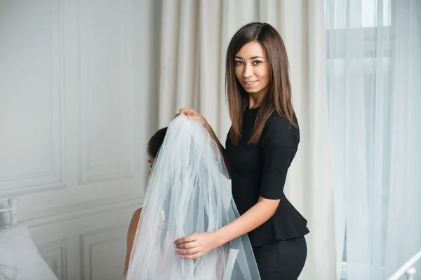 Beautiful girl is preparing for the wedding. Girlfriend sitting in the wedding veil