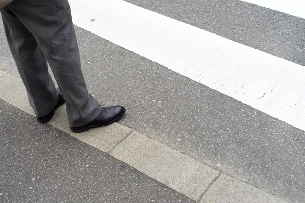 Man legs in slag pants waiting to cross the street at a crosswal